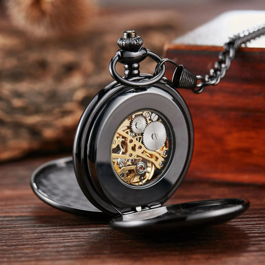 Montre à Gousset Mécanique Chasseur Homme coloris noir, boîtier ouvert côté fond montrant le mouvement à travers la fenêtre, posée sur bois